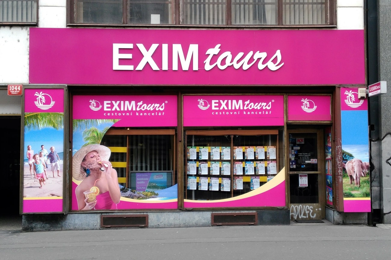 Exim Tours Opinie 2025: Wszystko, Co Musisz Wiedzieć Przed Rezerwacją Front view of EXIM tours travel agency with bright pink signage and travel posters in the windows.