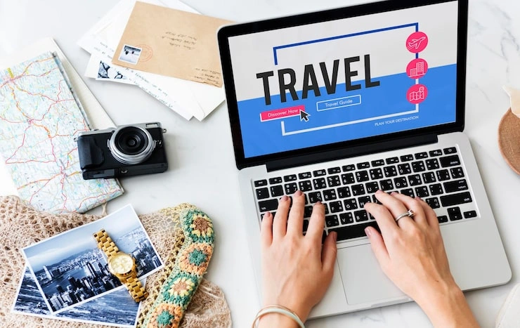Exim Tours Opinie 2025: Wszystko, Co Musisz Wiedzieć Przed Rezerwacją Person planning a trip on a laptop with travel-related items like a map, camera, and postcards nearby.