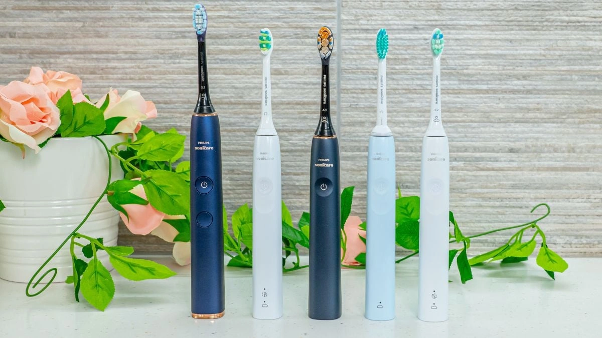 Najlepsza szczoteczka soniczna 2025 – Które Modele Naprawdę Dbają O Twoje Zęby? Pięć szczoteczek elektrycznych Philips Sonicare w kolorach czarnym i białym, zaprezentowanych na tle zielonych liści i kwiatów.