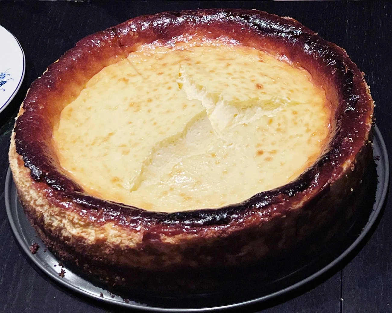 Jak Zrobić Sernik Idealny? Sprawdzone Triki, Które Działają Za Każdym Razem Burnt-rim cheesecake with a large crack in the center, showing a beginner baking mishap.
