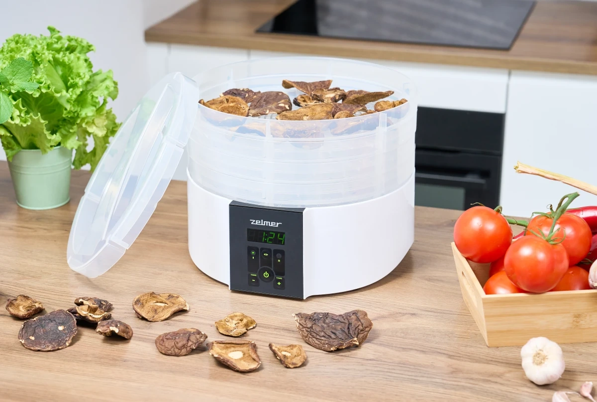 Zelmer ZFD2020 food dryer with dried mushrooms on trays and fresh vegetables on kitchen counter