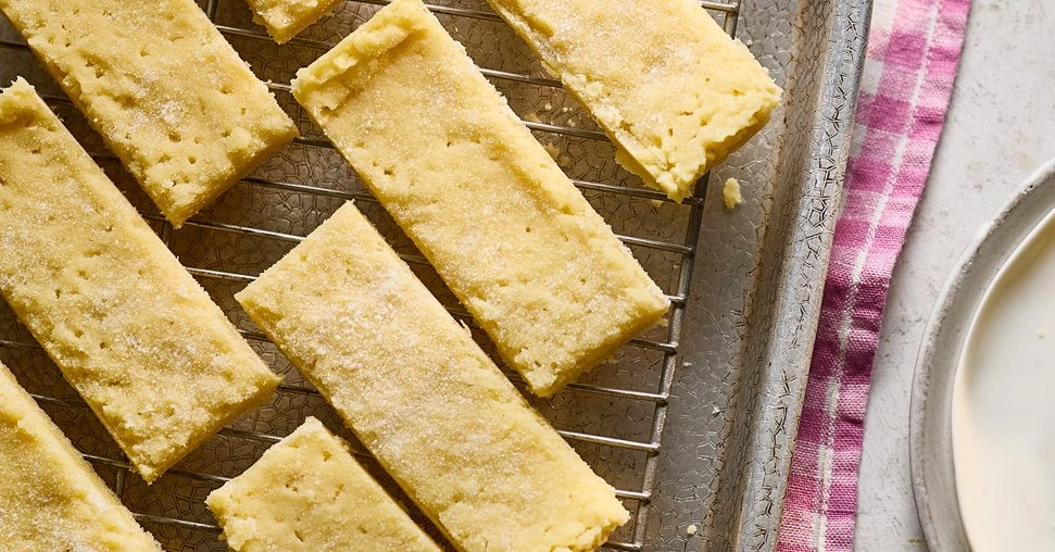 Jak Zrobić Domowe Przekąski Bezglutenowe w 15 Minut Gluten-free shortbread cookies cooling on a wire rack next to a pink striped cloth and a bowl of cream.