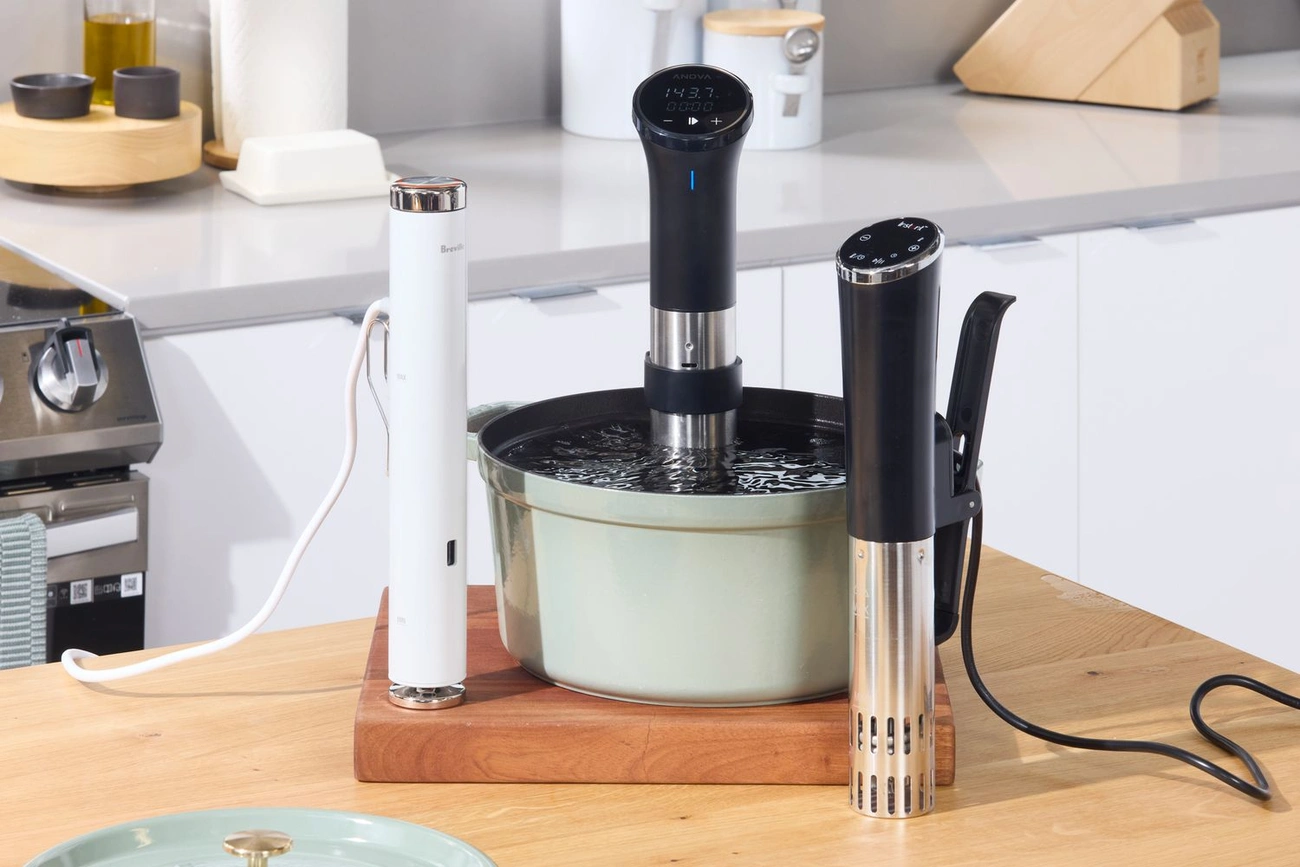 Pierwszy Zakup Sprzętu Sous Vide? Oto Co Musisz Wiedzieć Four top sous vide immersion circulators of 2025 displayed on a kitchen countertop with one in a pot of water.