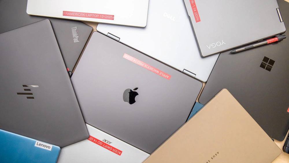 Top view of laptops from the 7 best brands of 2025 including Apple, Dell, Lenovo, HP, Asus, Acer, and Framework.