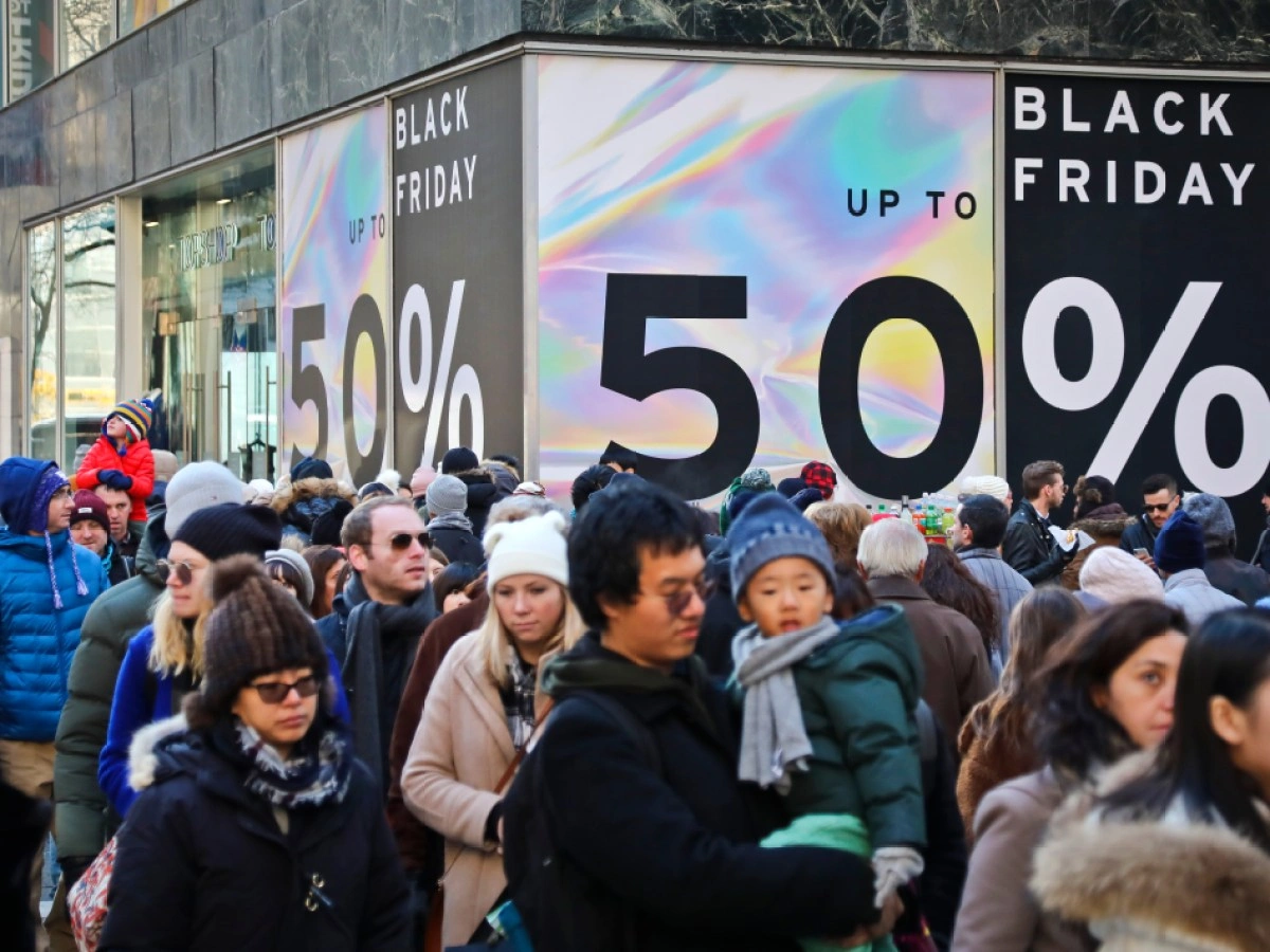 Nie Daj Się Nabrać na Black Friday 2025: Jak Kupować Mądrze? Crowd of shoppers outside a store with large Black Friday signs advertising up to 50% off sales.